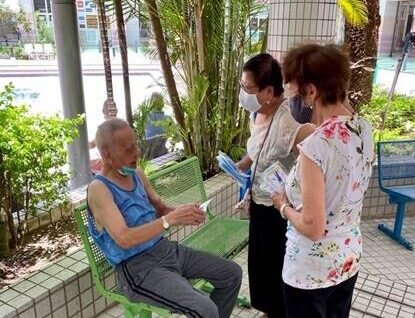 Ann and Carol hand a Gospel tract to a senior citizen in Hong Kong